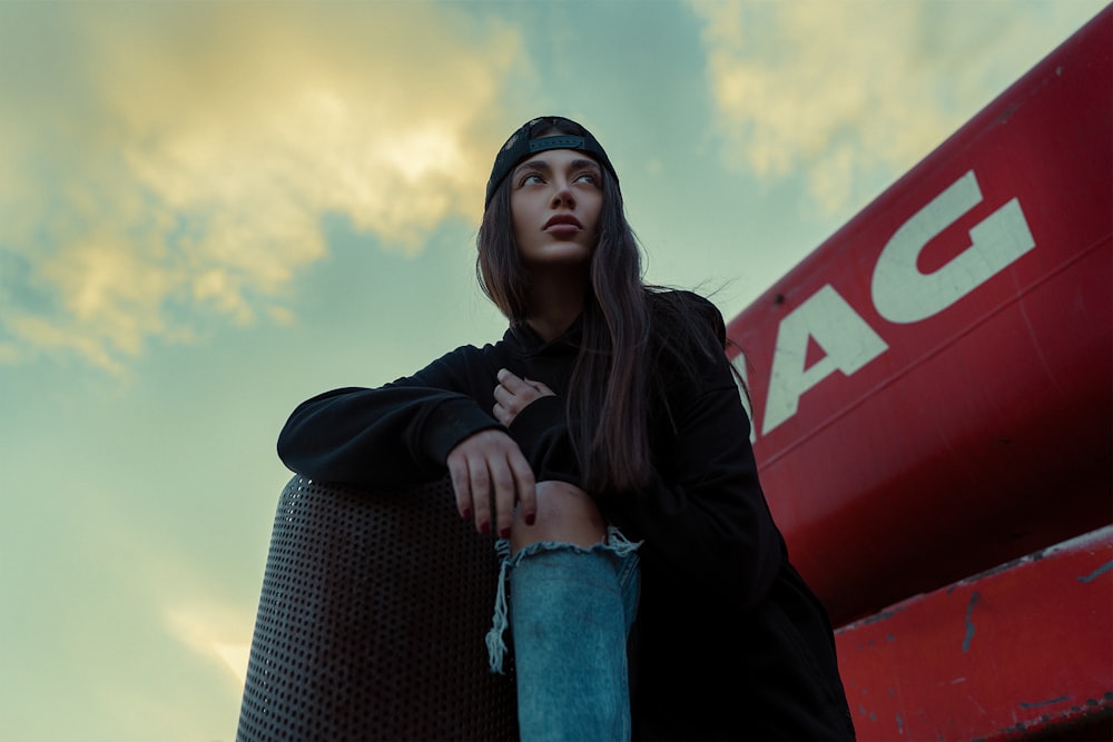 a woman sitting on top of a barrel next to a red sign