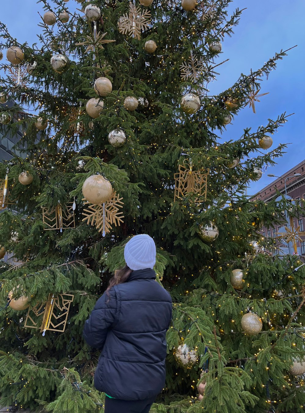 a woman standing in front of a christmas tree