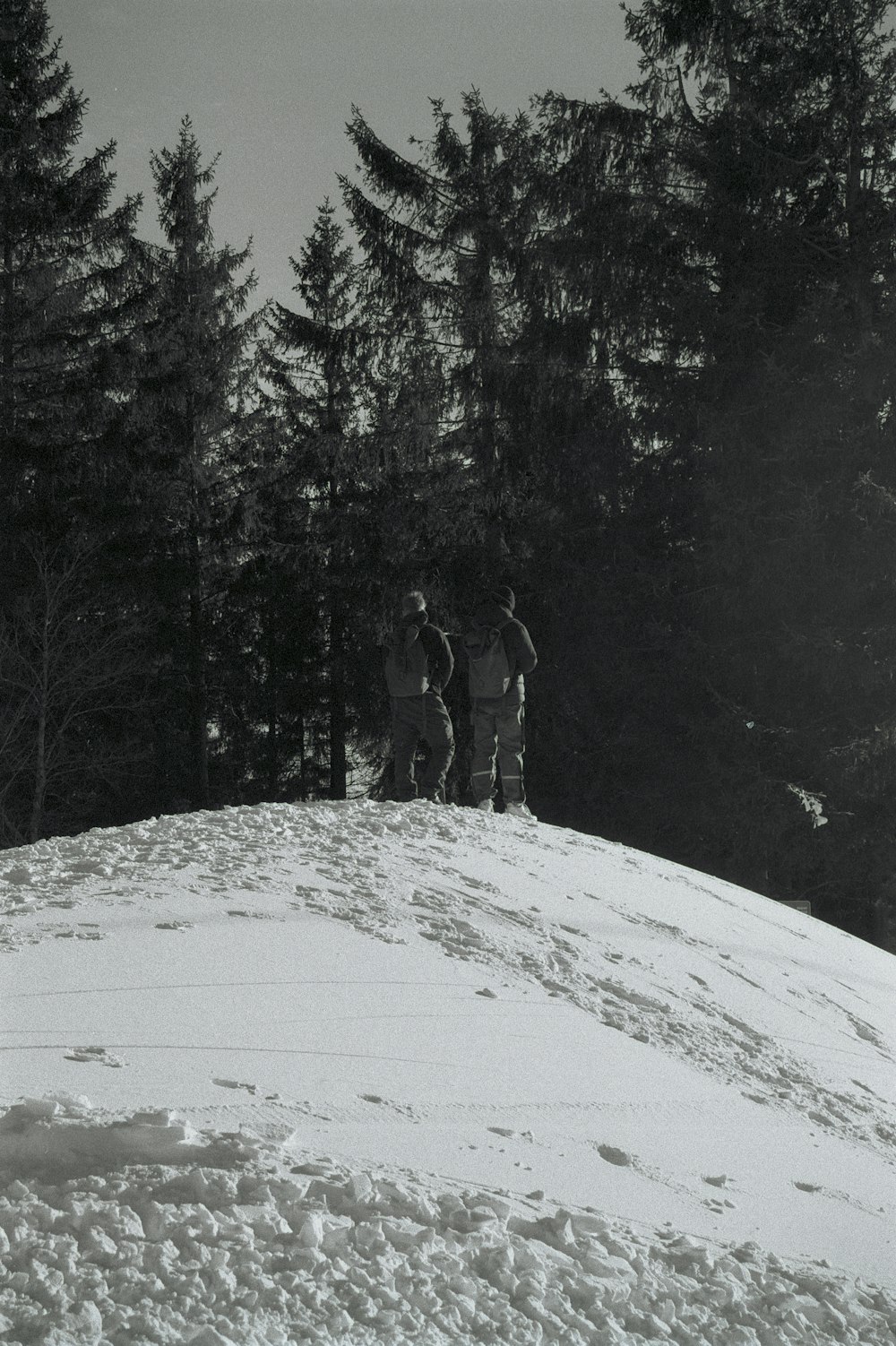 a couple of people standing on top of a snow covered slope