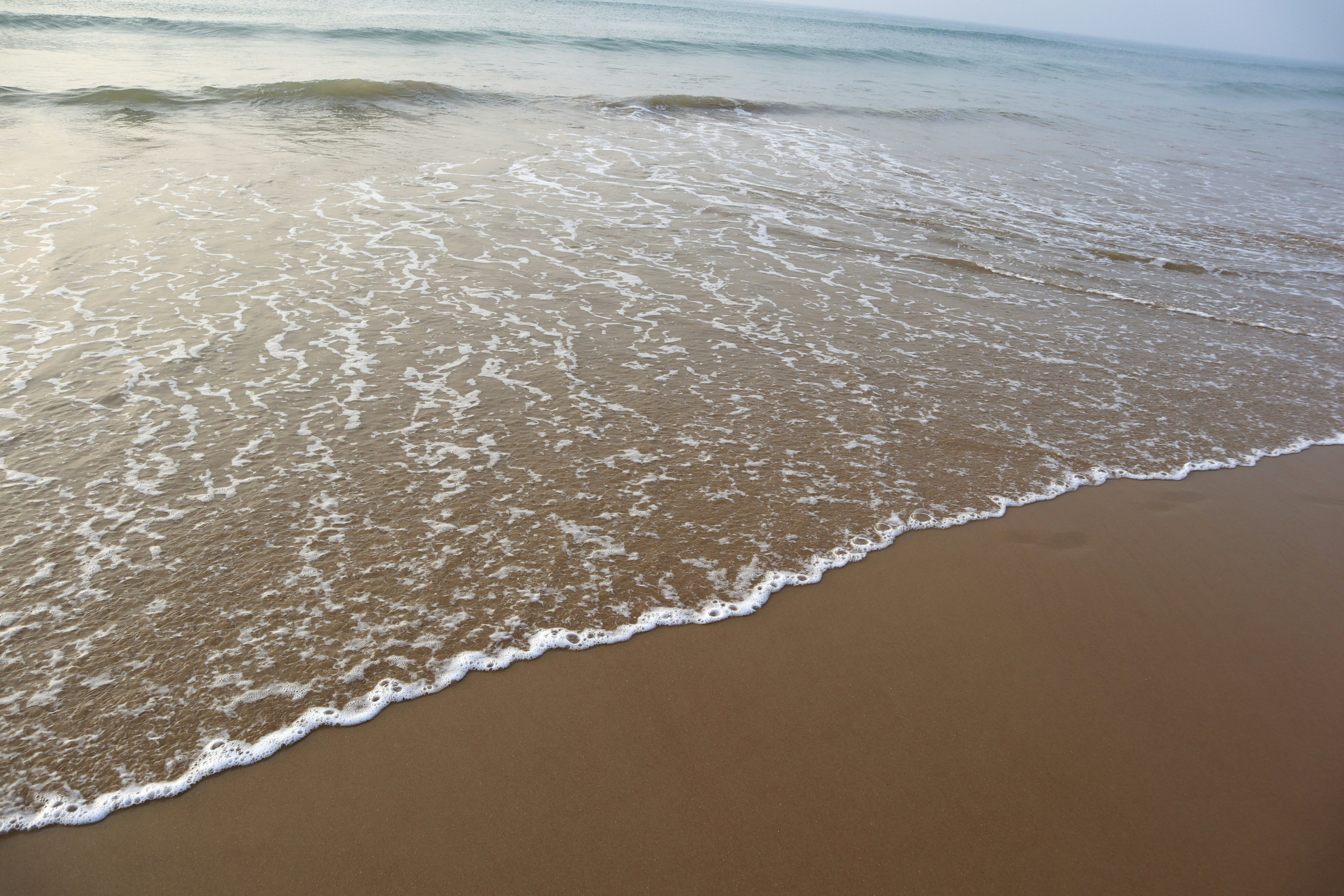 a sandy beach with waves coming in to shore