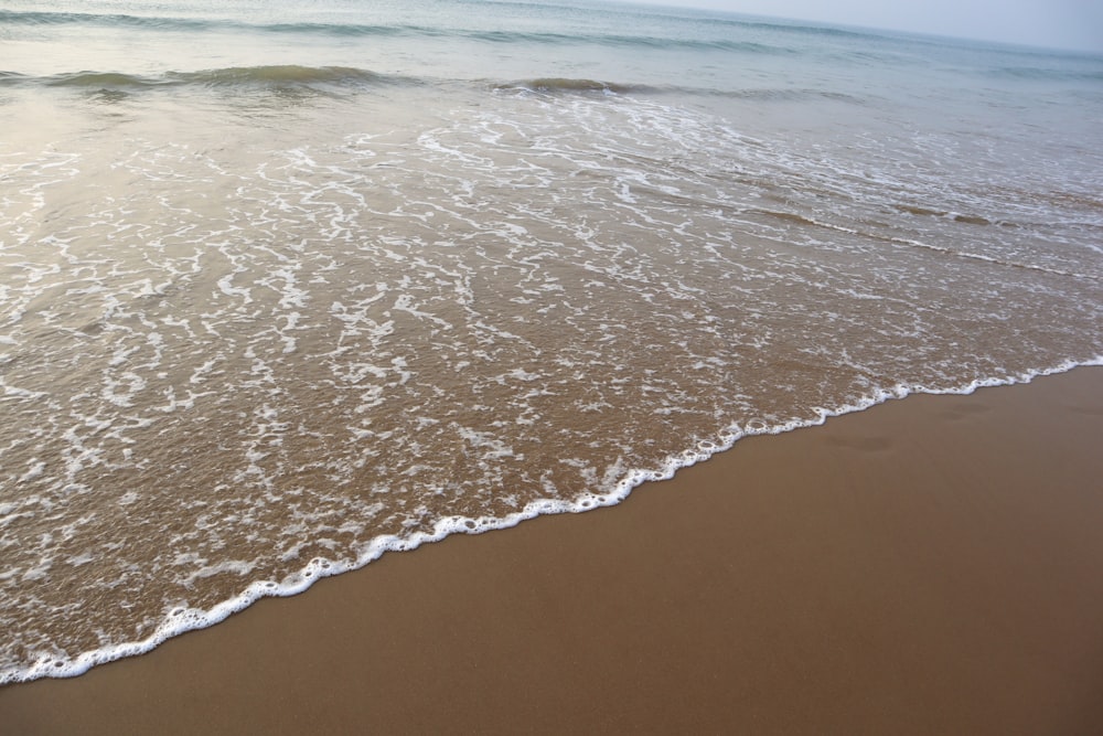 a sandy beach with waves coming in to shore