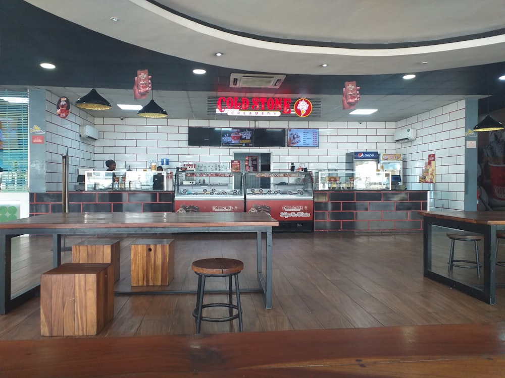 the inside of a fast food restaurant with tables and stools