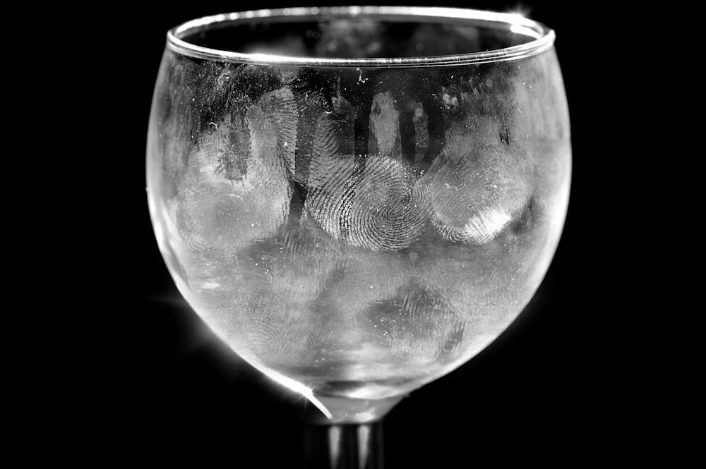 uma taça de vinho cheia de água em um fundo preto