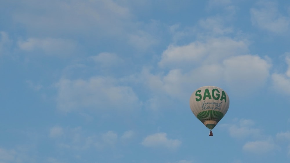 a hot air balloon flying through a blue cloudy sky