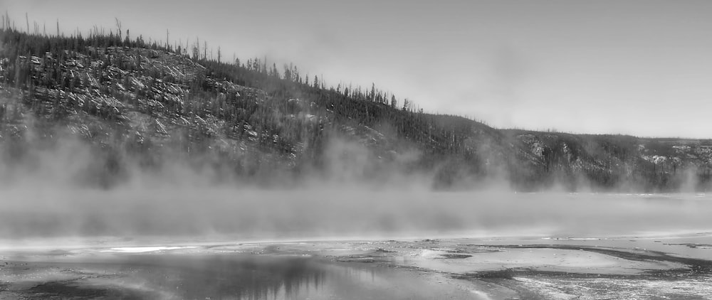 a black and white photo of a foggy lake