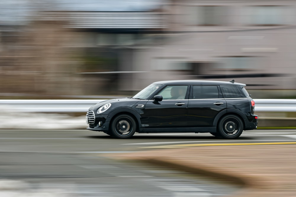 Une Mini Cooper noire conduisant dans une rue