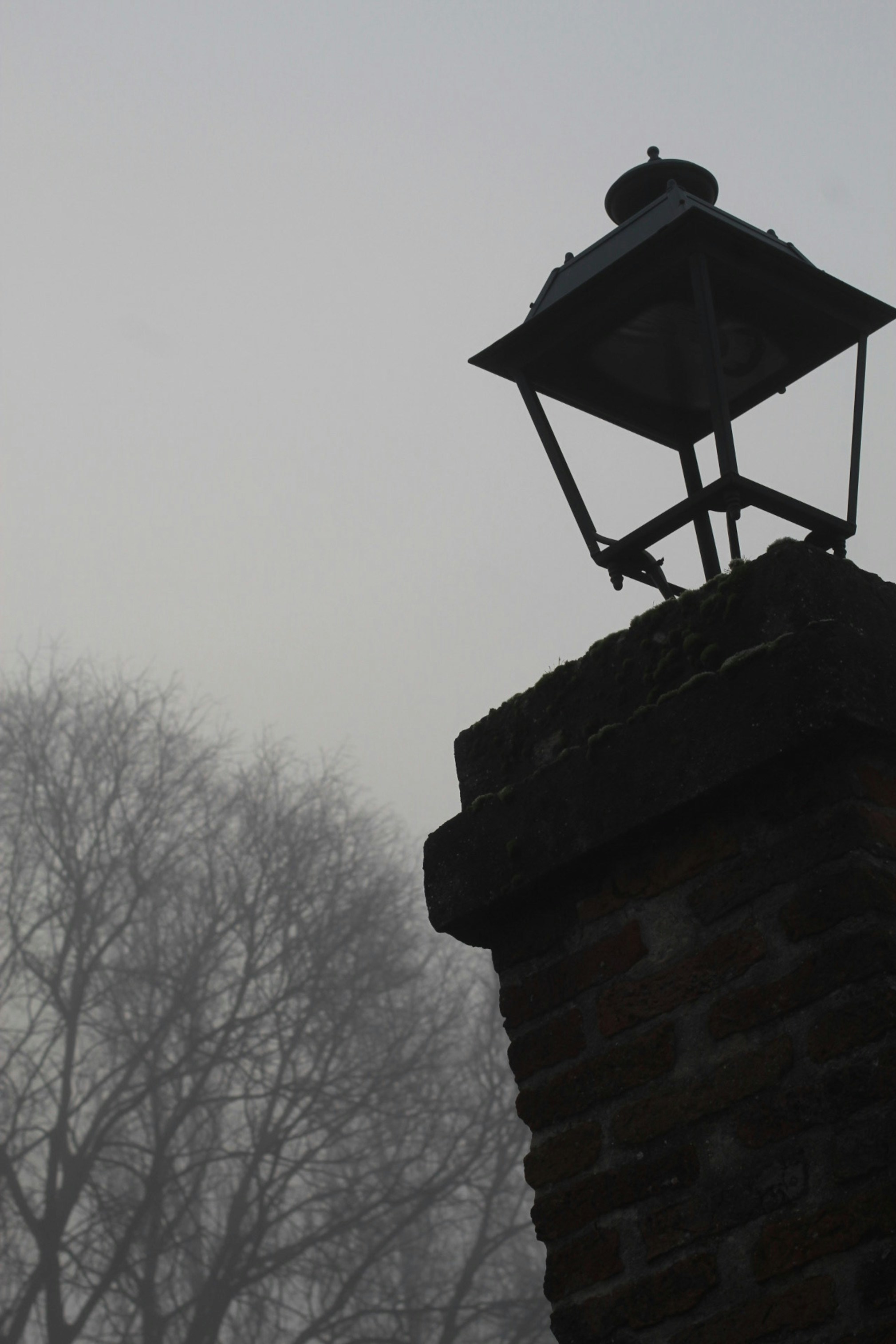 un lampadaire assis au sommet d’un mur de briques