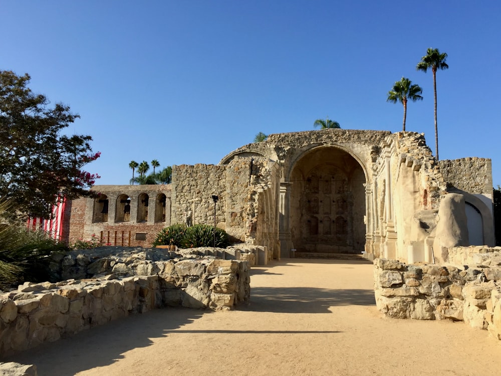 a stone building with palm trees in the background