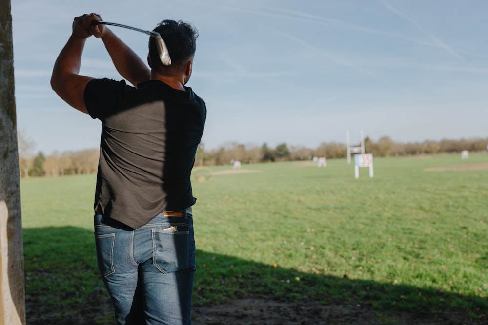 un hombre balanceando un palo de golf en un campo