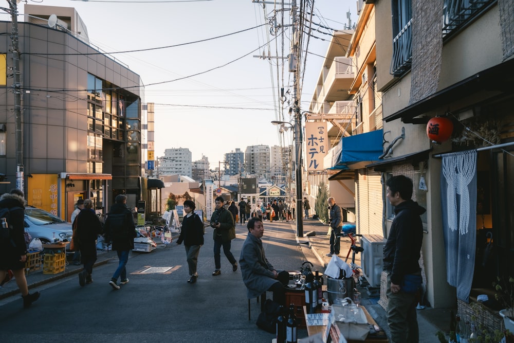 a group of people walking down a street next to tall buildings