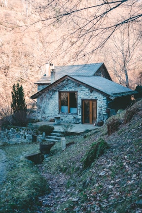 a stone house sitting on top of a lush green hillside