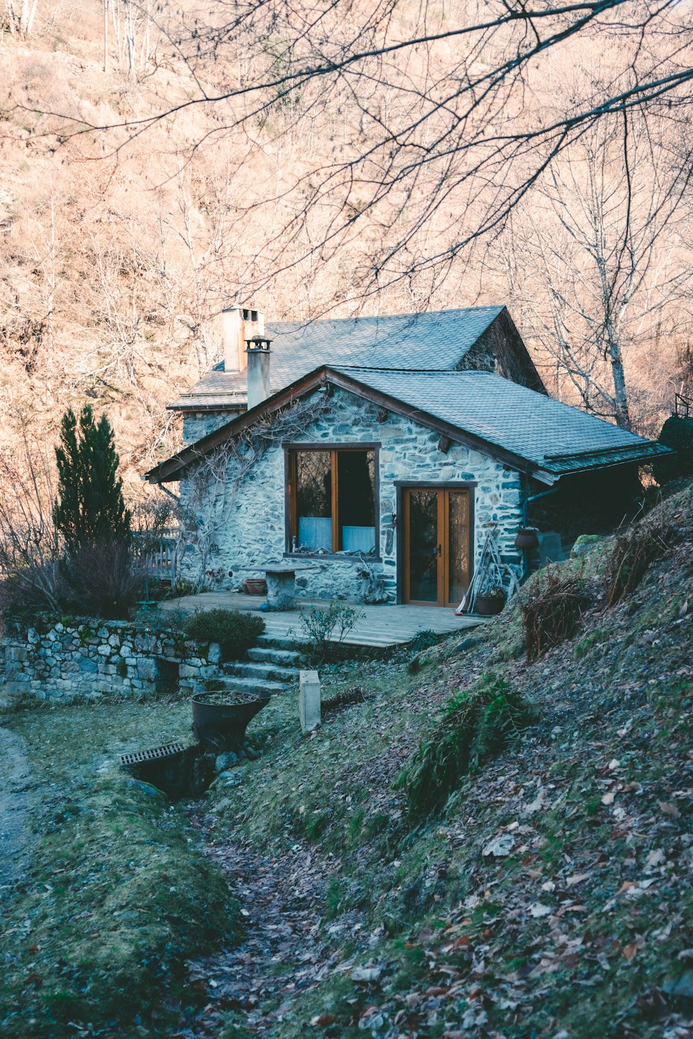 a stone house sitting on top of a lush green hillside