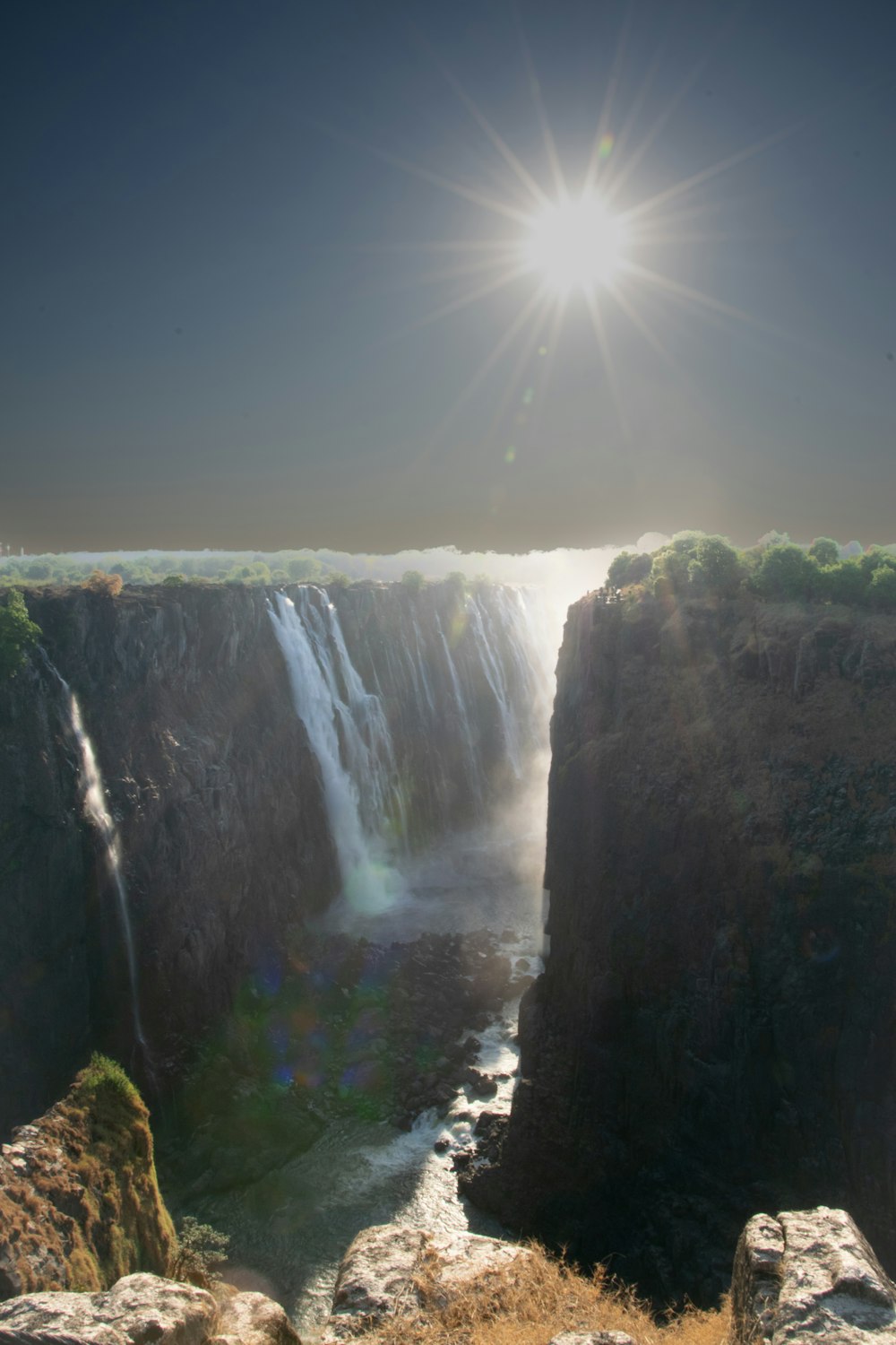 the sun shines brightly over a large waterfall
