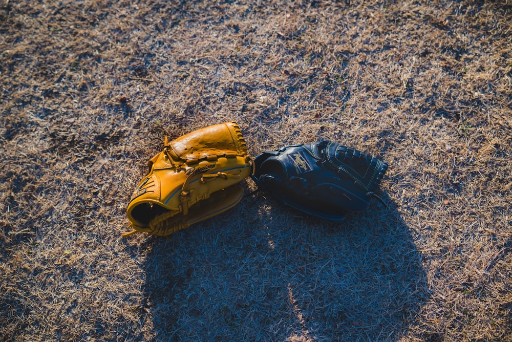 a pair of baseball gloves laying on the ground