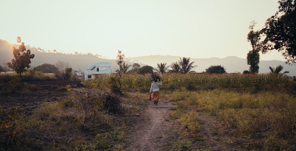 a person walking down a dirt path in a field