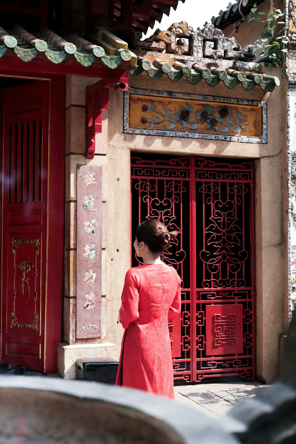 a woman in a red dress standing in front of a red door