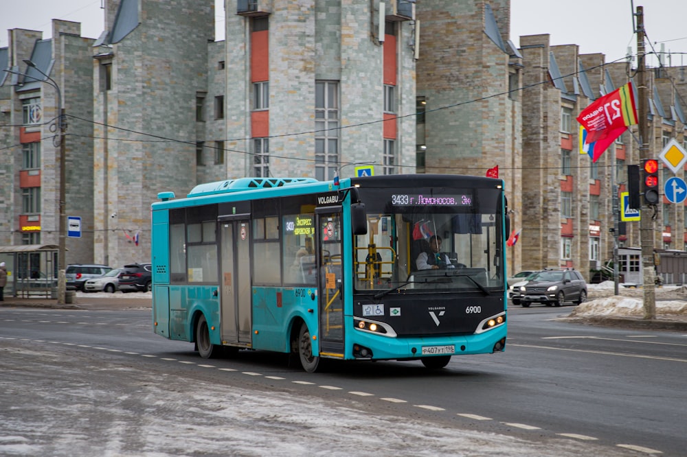 a blue bus driving down a street next to tall buildings