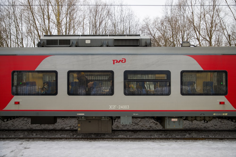 a red and silver train car sitting on the tracks