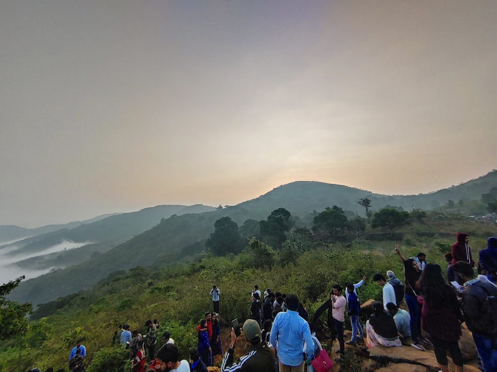 a group of people standing on top of a lush green hillside