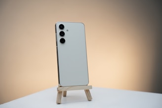 a white cell phone sitting on top of a wooden stand