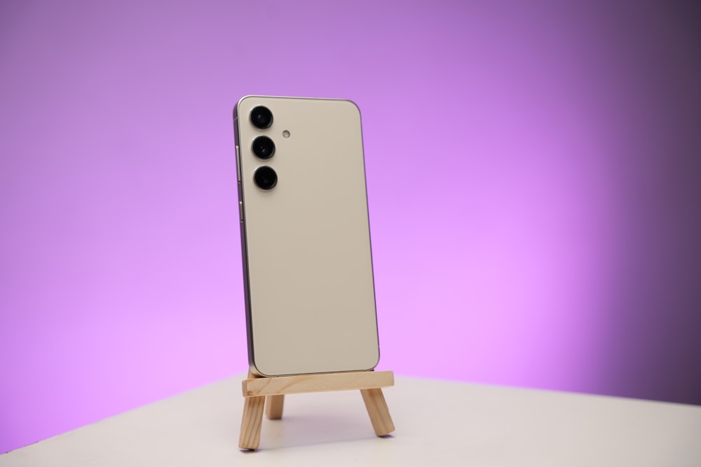 a cell phone on a wooden stand with a purple background