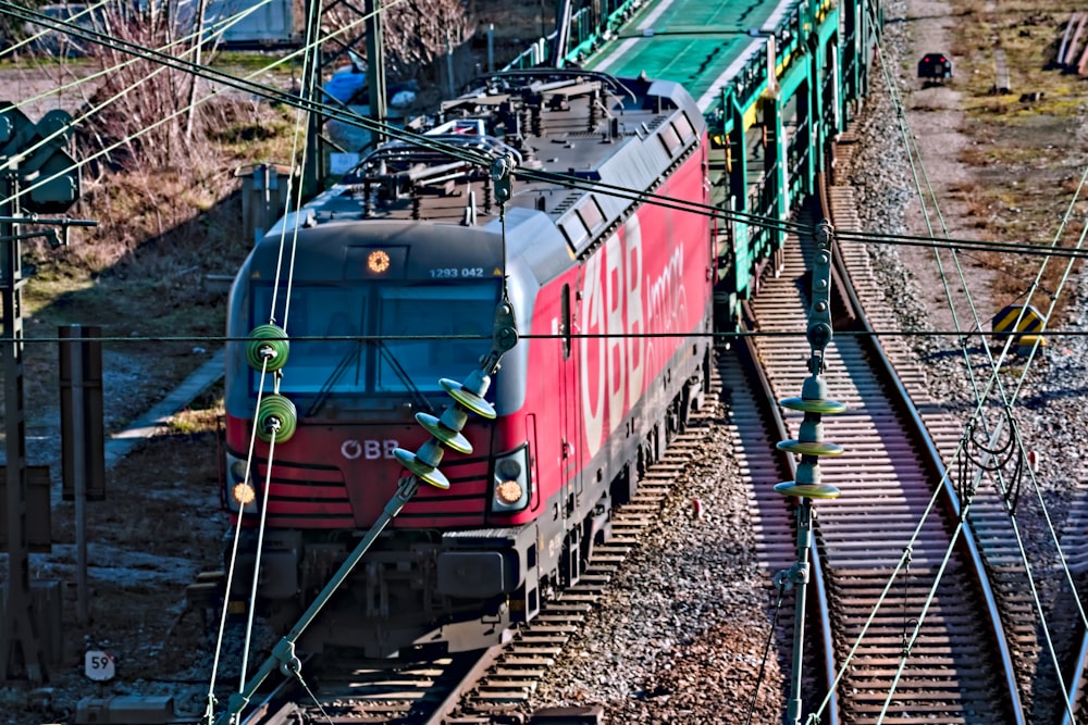 a red train traveling down train tracks next to power lines