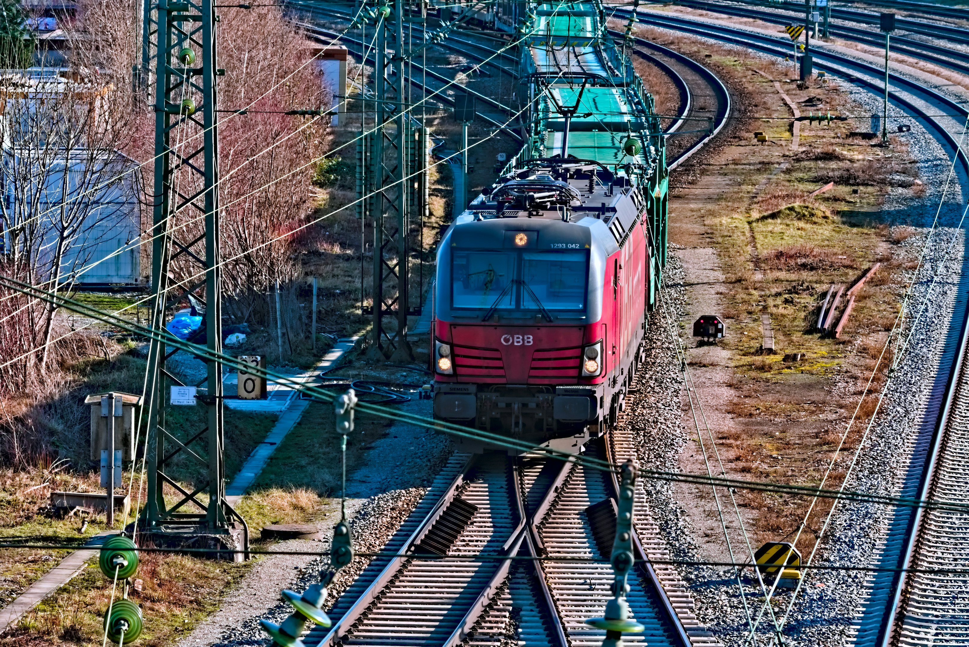 a red train traveling down train tracks next to a forest