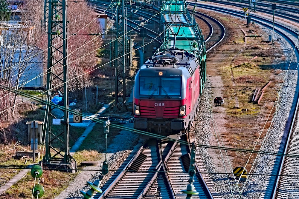 a red train traveling down train tracks next to a forest