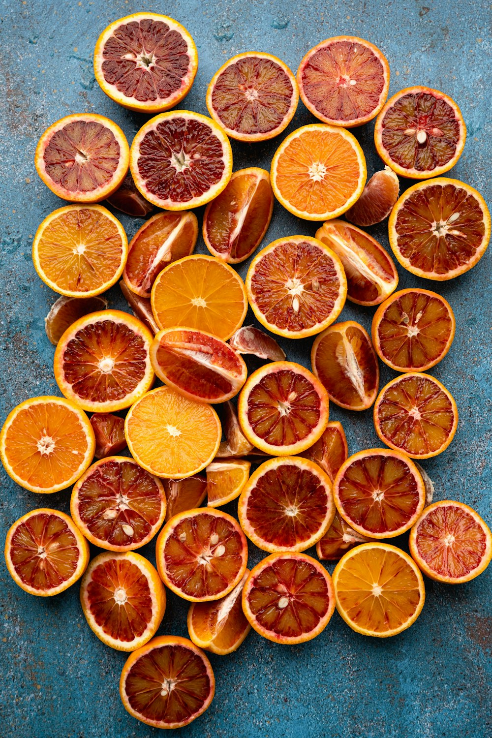 a pile of oranges cut in half on a blue surface