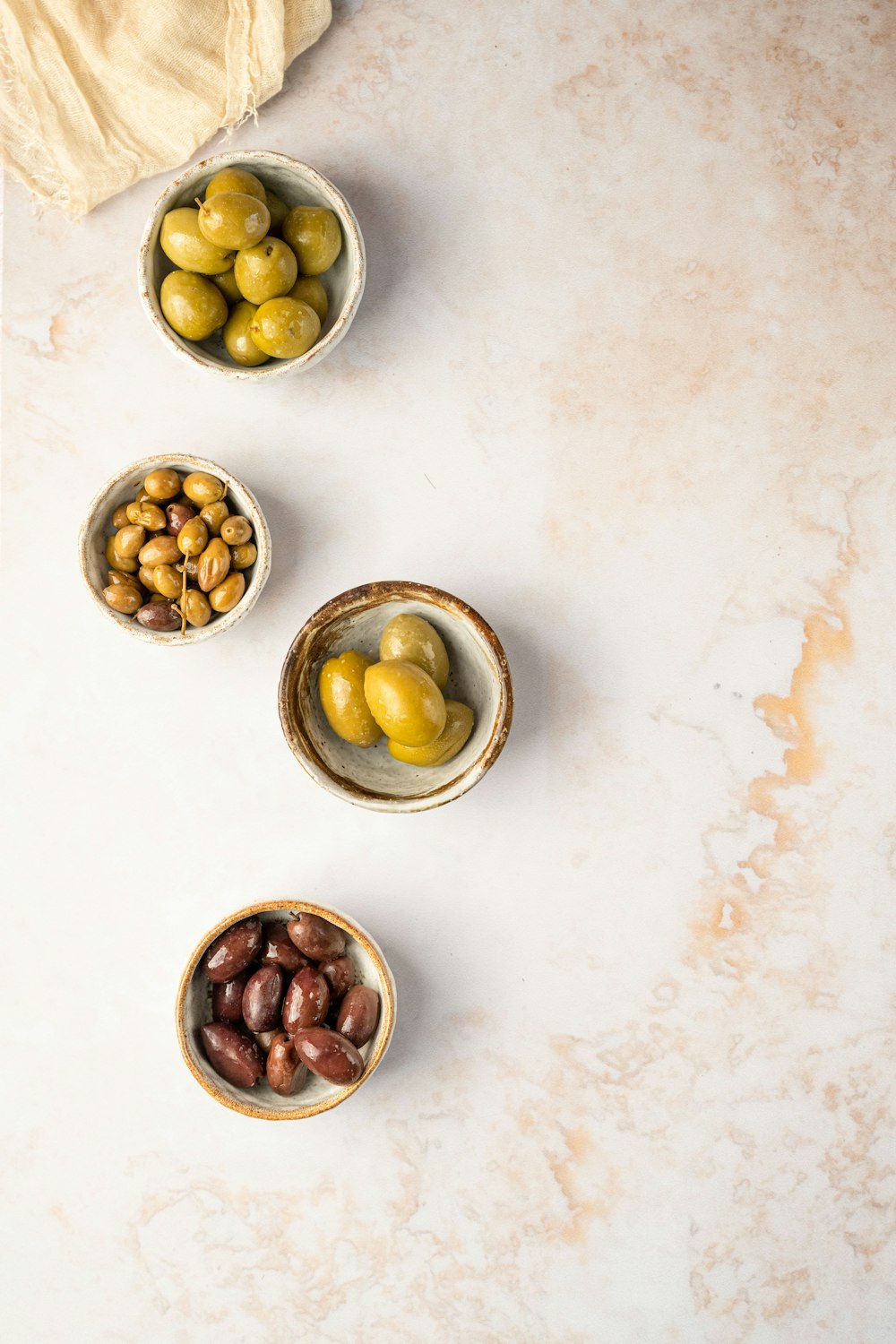 three bowls of olives and a towel on a table