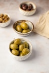 three bowls filled with olives on top of a table
