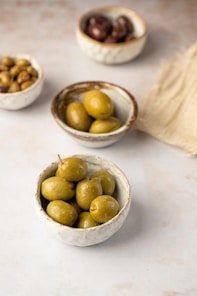 three bowls filled with olives on top of a table