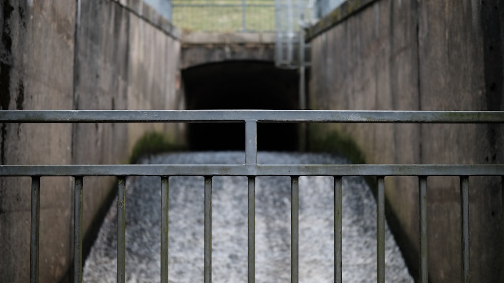 a gated entrance to a tunnel with water coming out of it