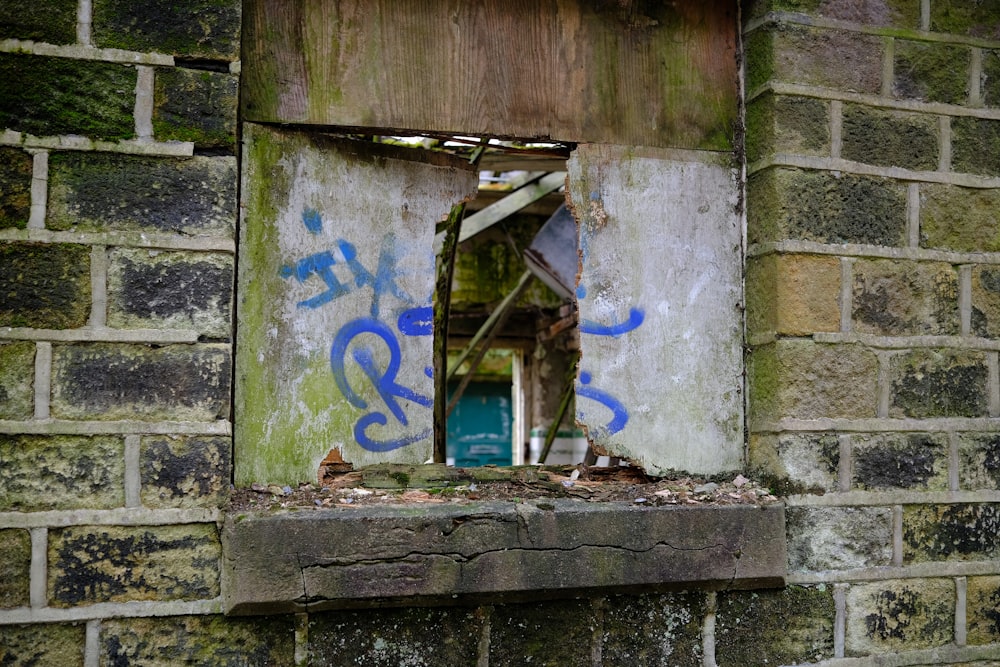 a window in a brick wall with graffiti on it