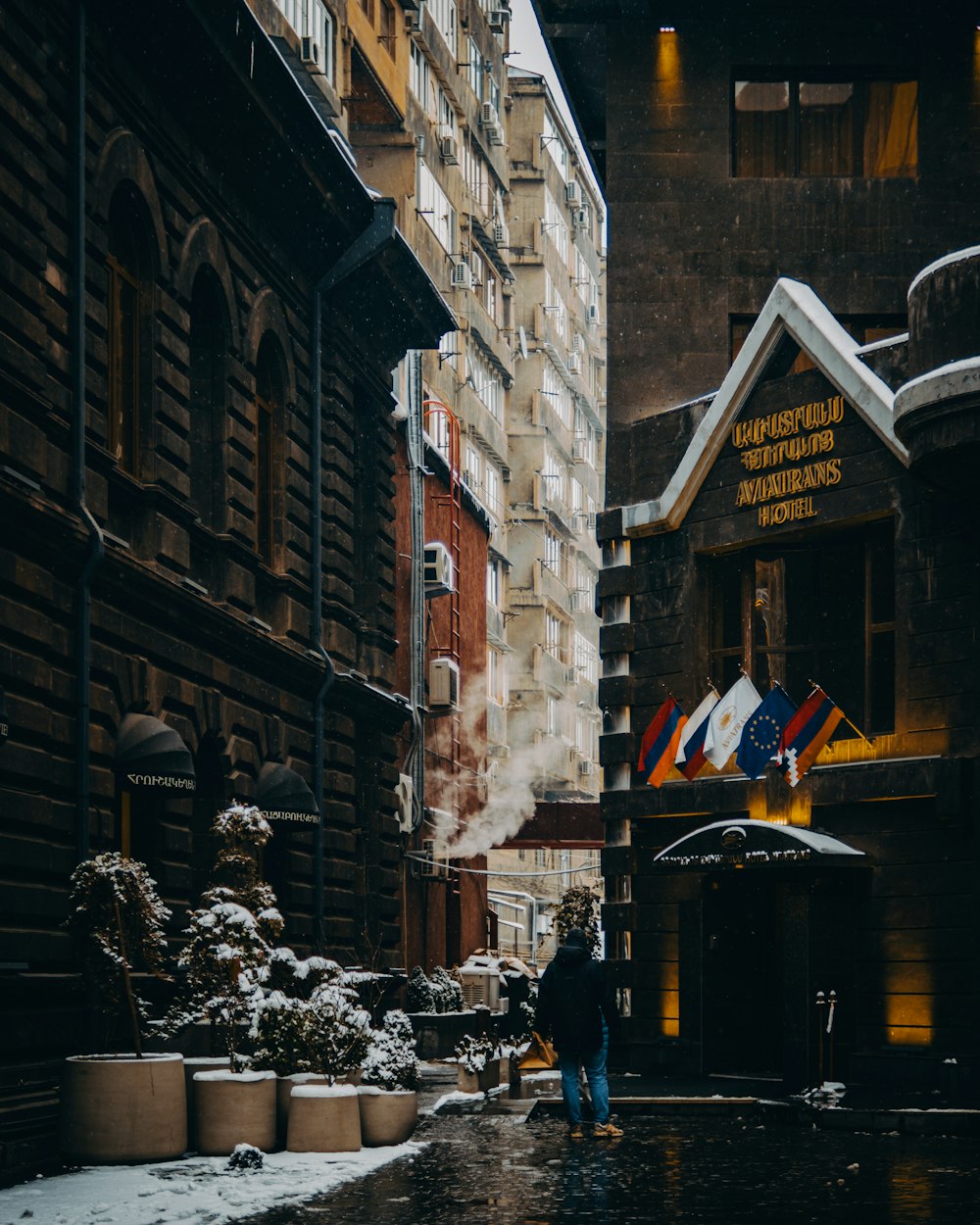 a man walking down a street next to tall buildings