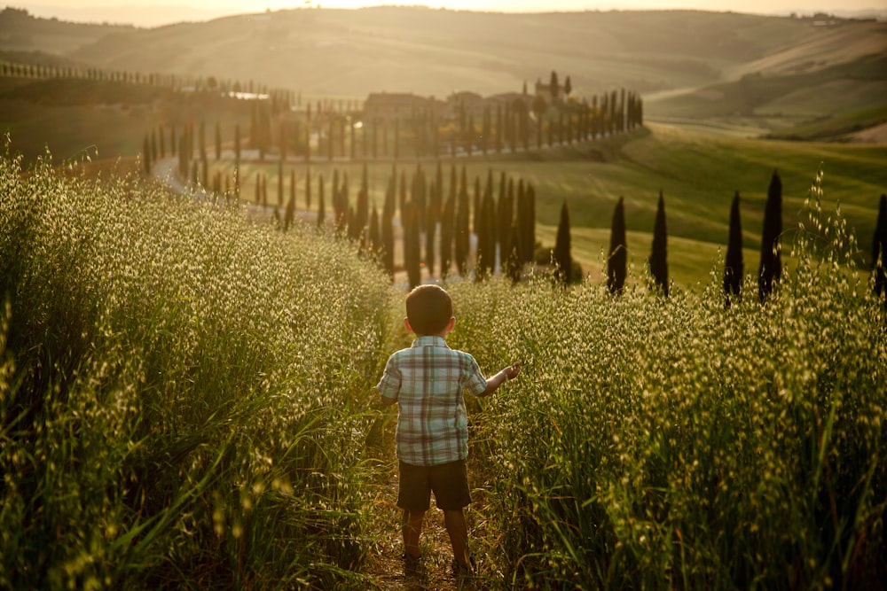 a young boy standing in a field of tall grass