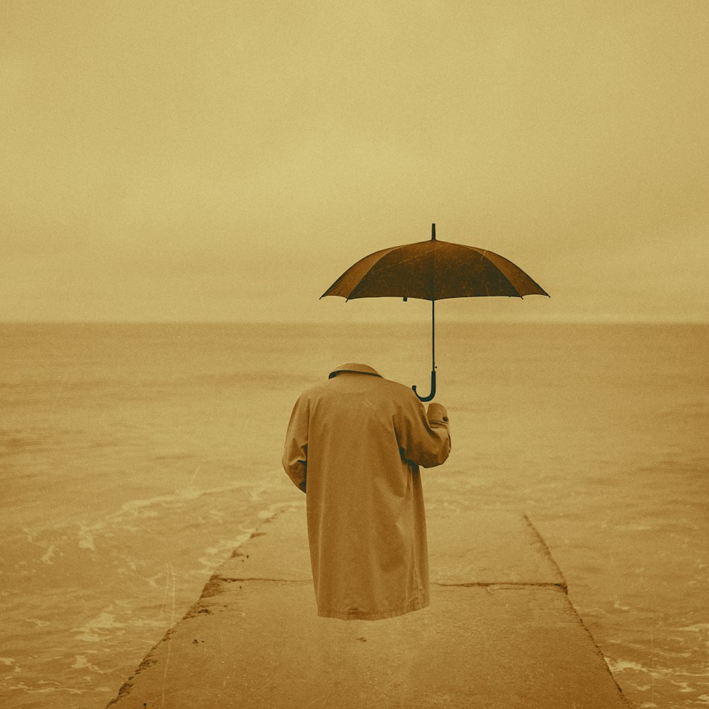 a man walking on a pier holding an umbrella