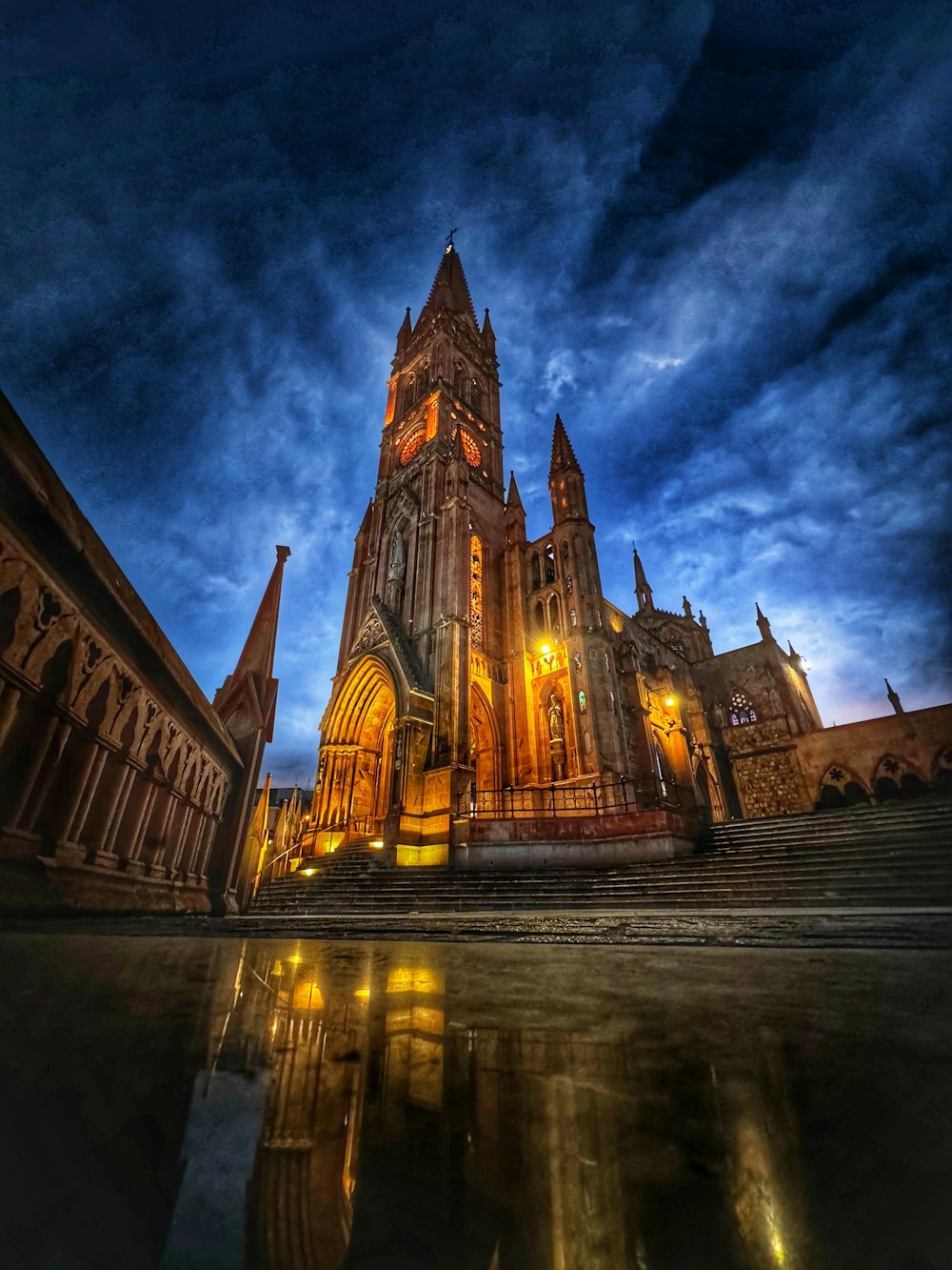 a large cathedral with a clock tower lit up at night