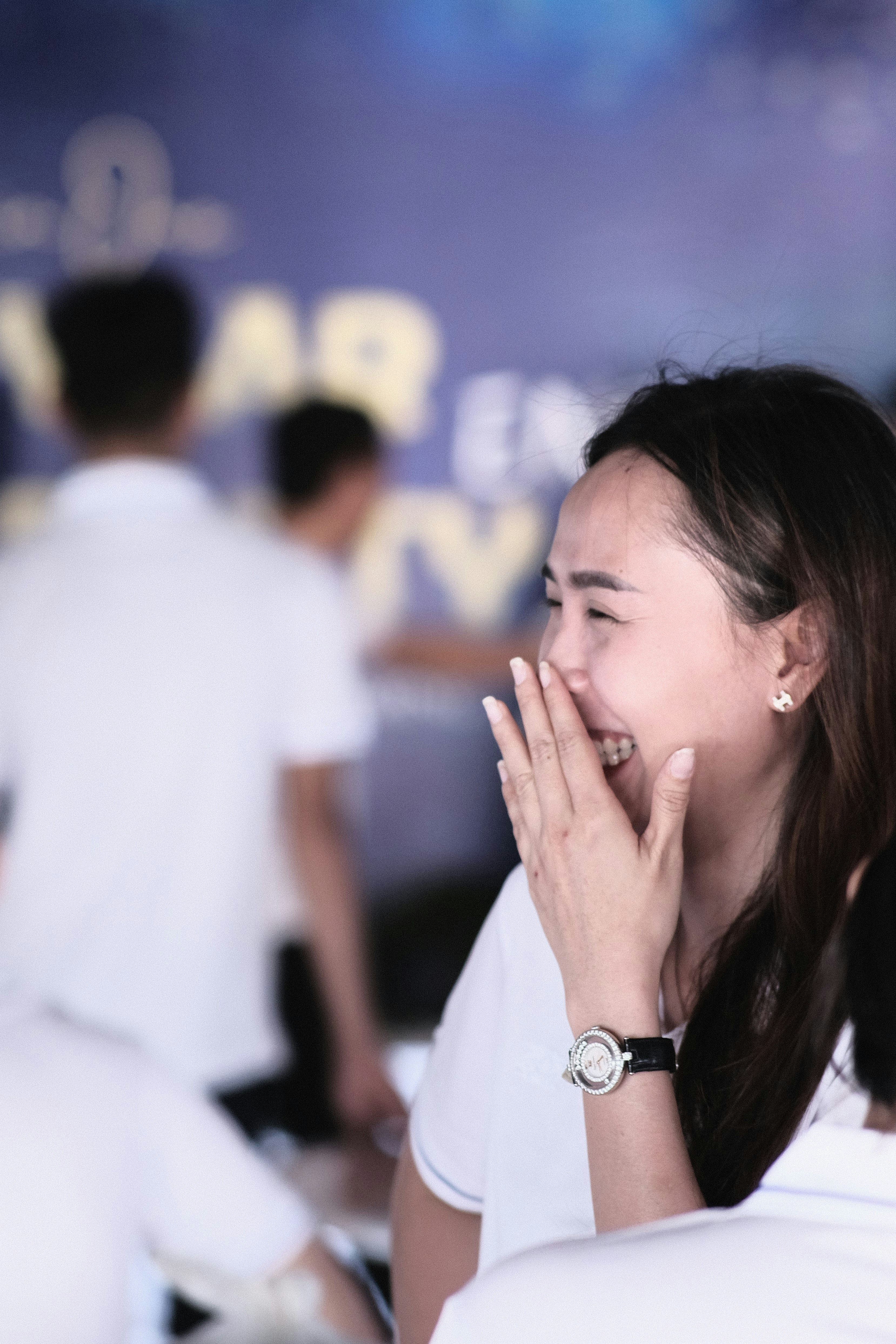 a woman is laughing and holding her hands to her face