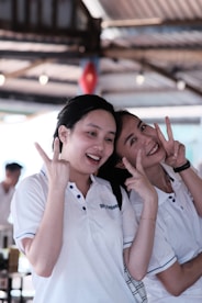 two women standing next to each other giving the peace sign