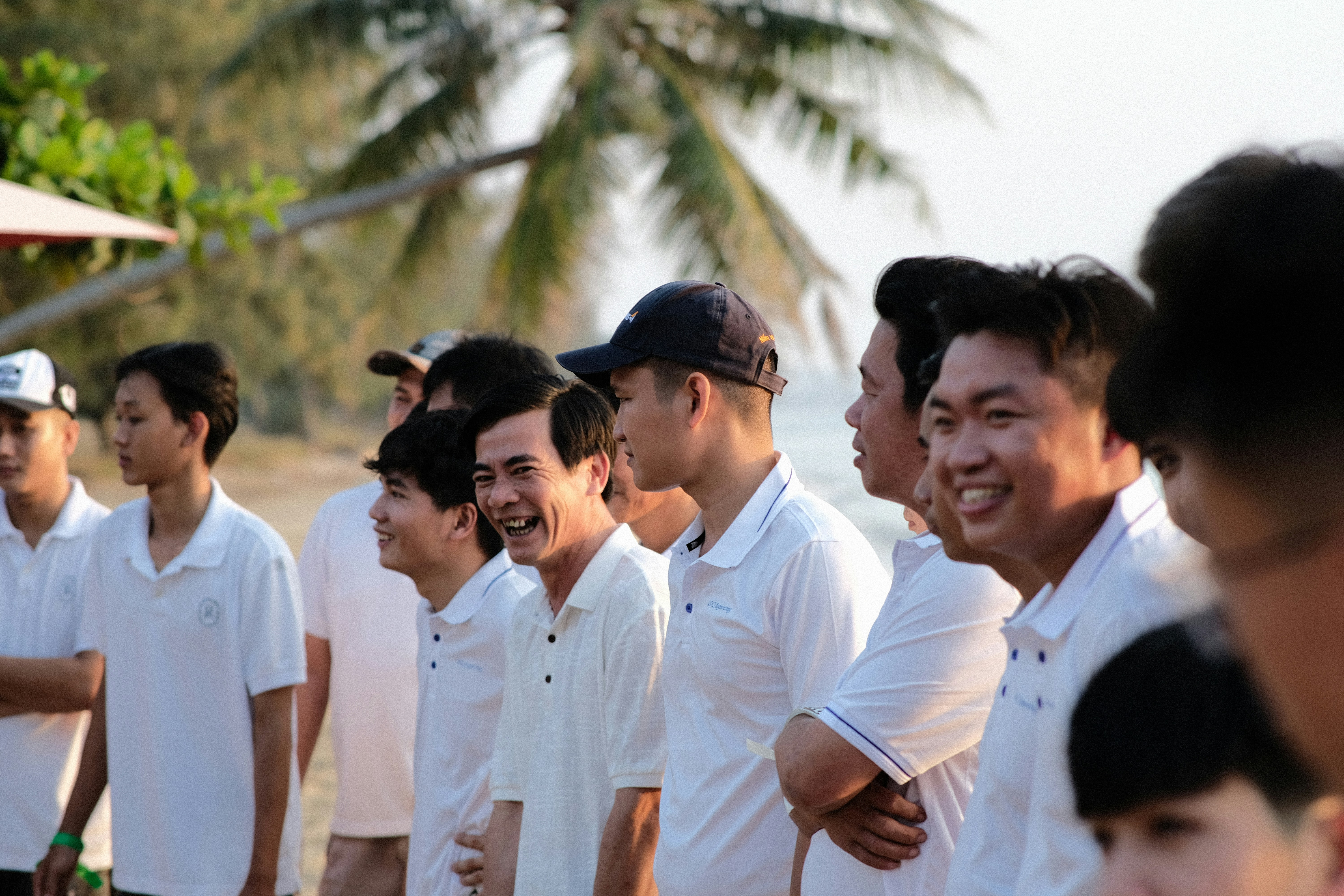sekelompok pria berdiri bersebelahan di pantai