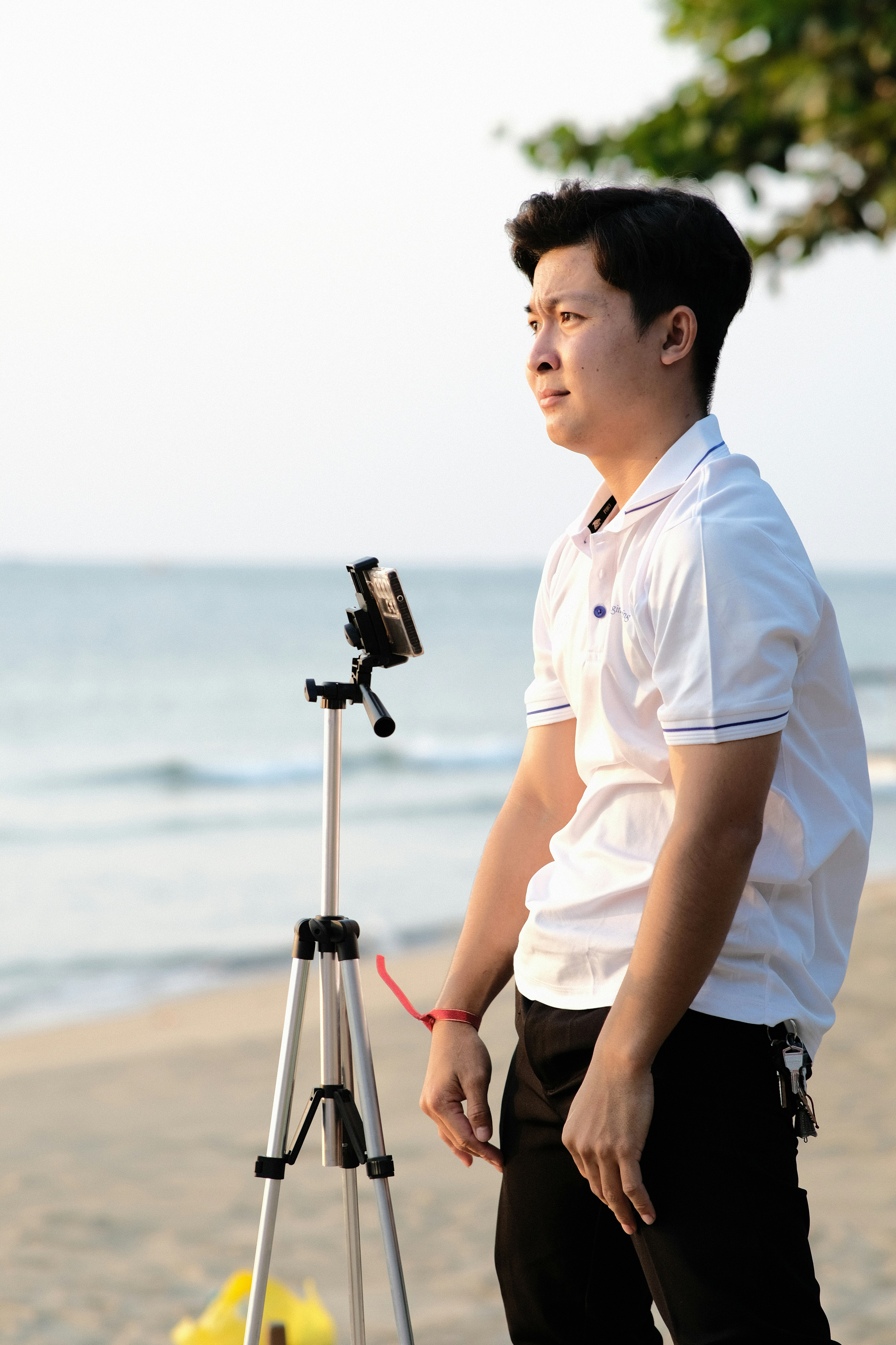 a man standing on a beach next to a tripod