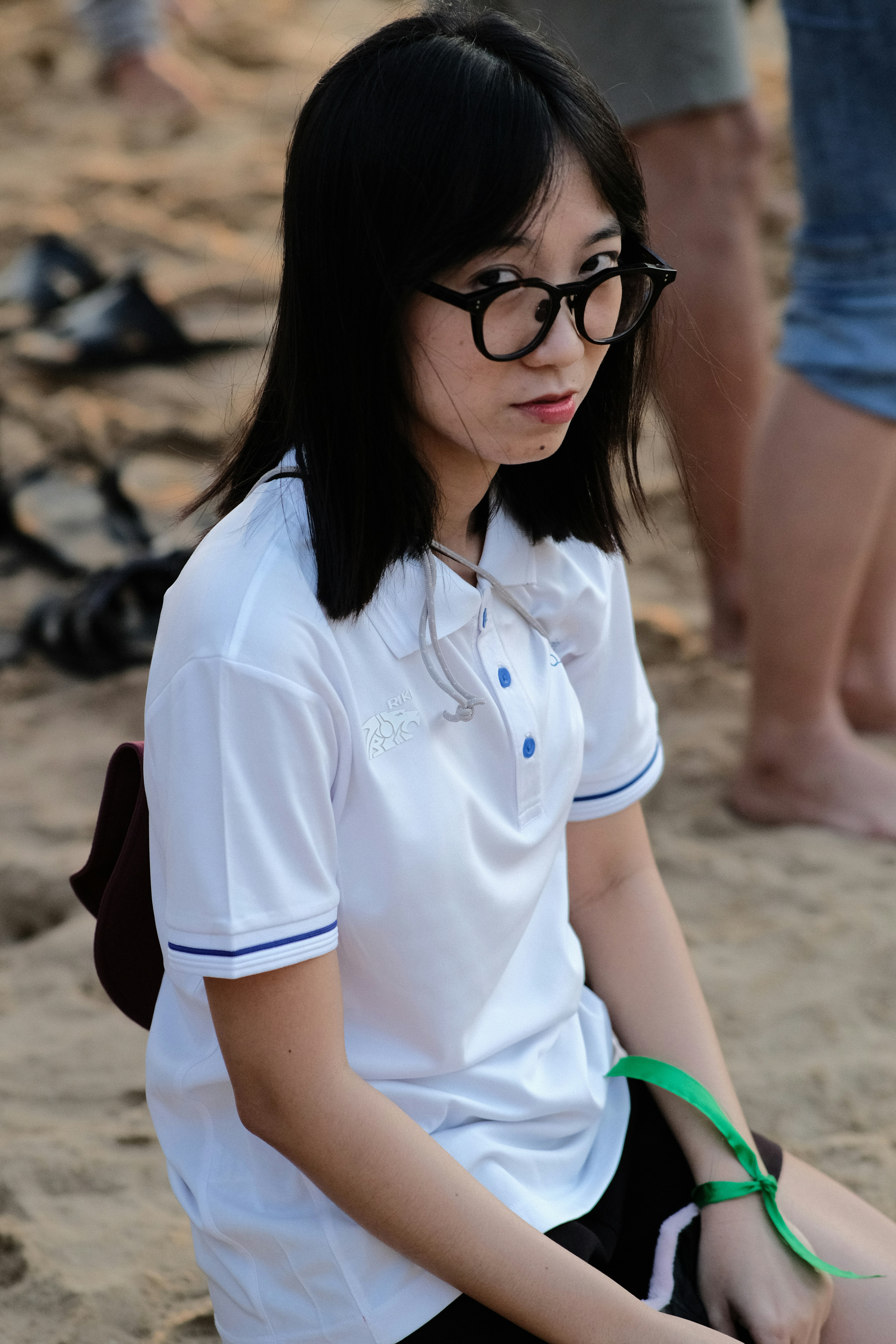 a woman sitting on the sand with a pair of scissors in her hand