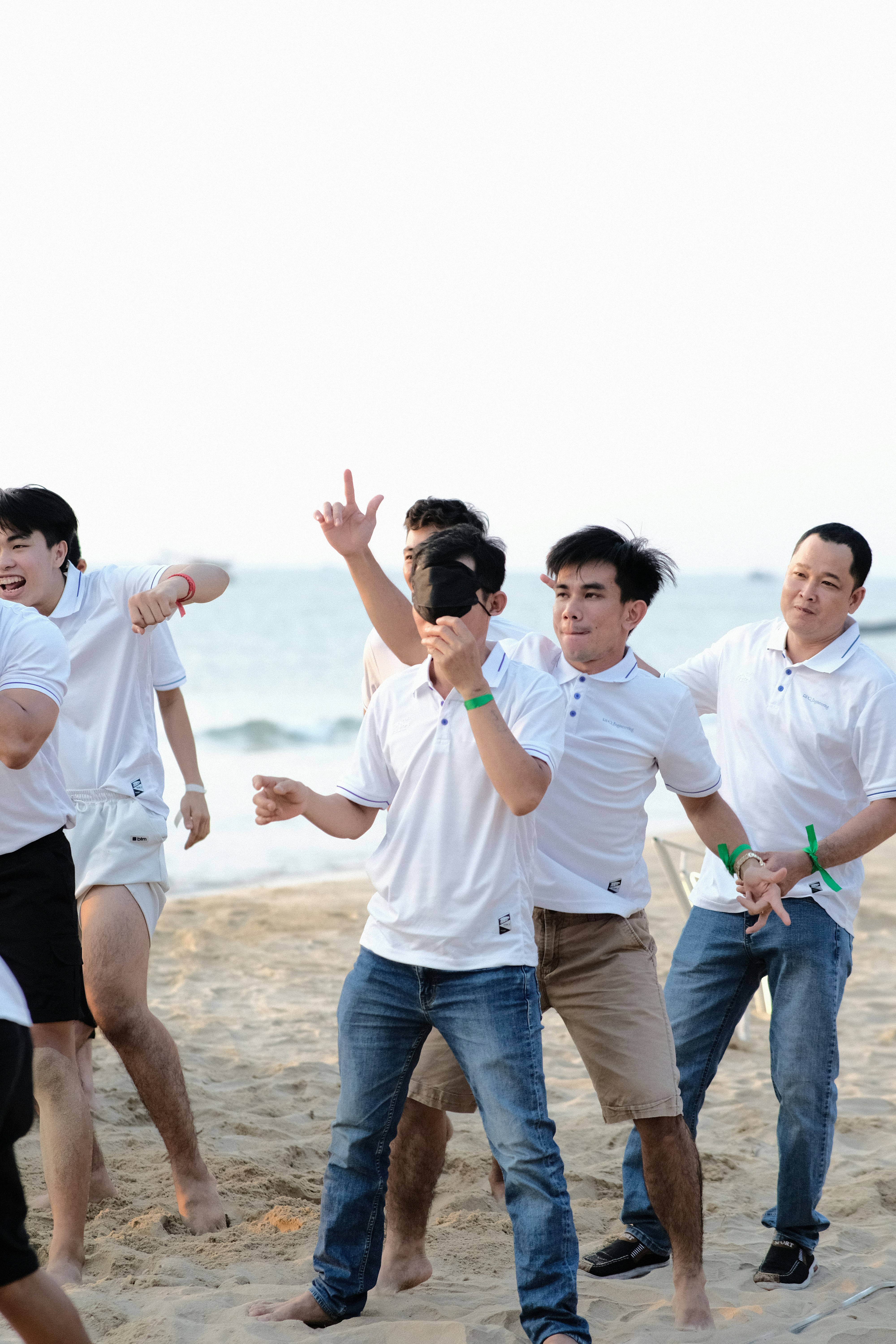 a group of men standing on top of a sandy beach