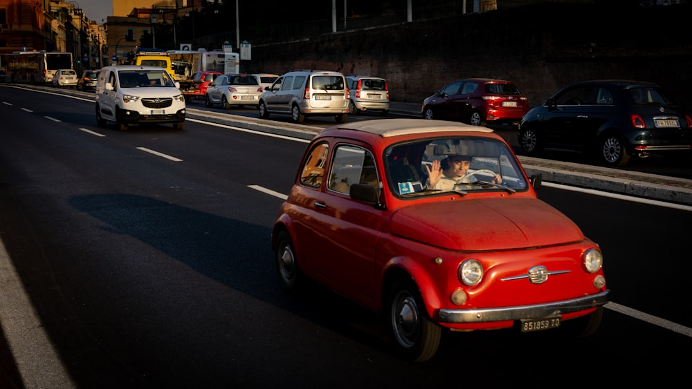 a red car driving down a street next to other cars