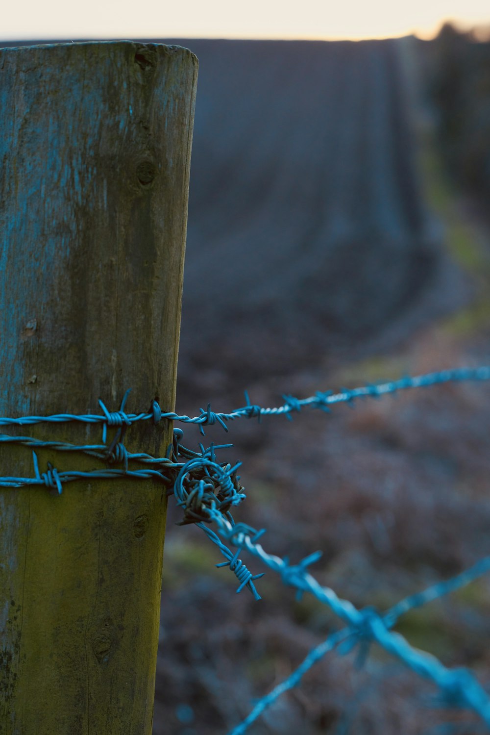 a close up of a fence post with barbed wire