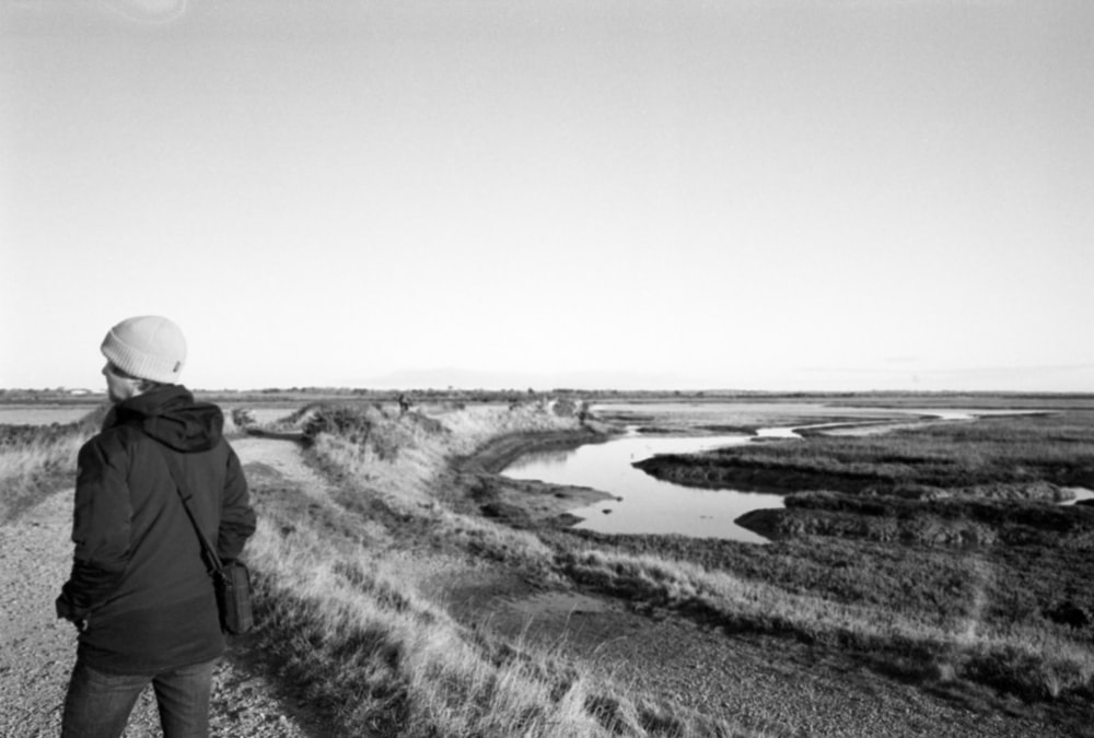 a person standing on a dirt road next to a body of water