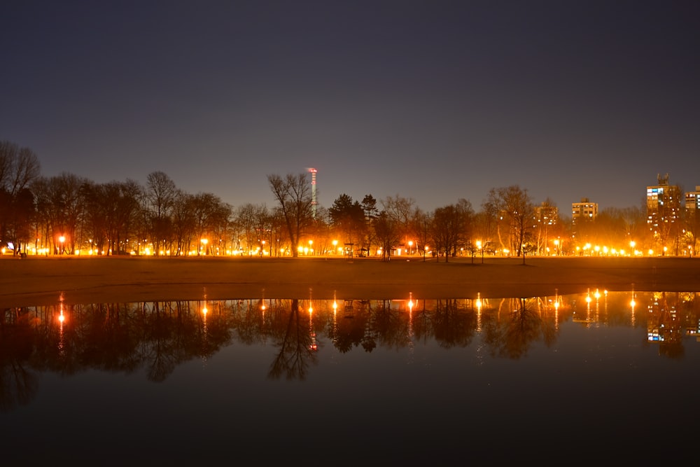 a city skyline is lit up at night with lights reflecting in the water