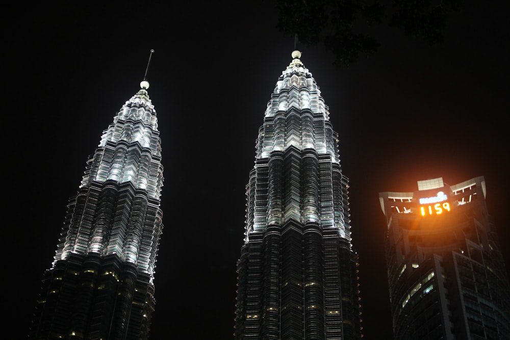 two very tall buildings lit up at night