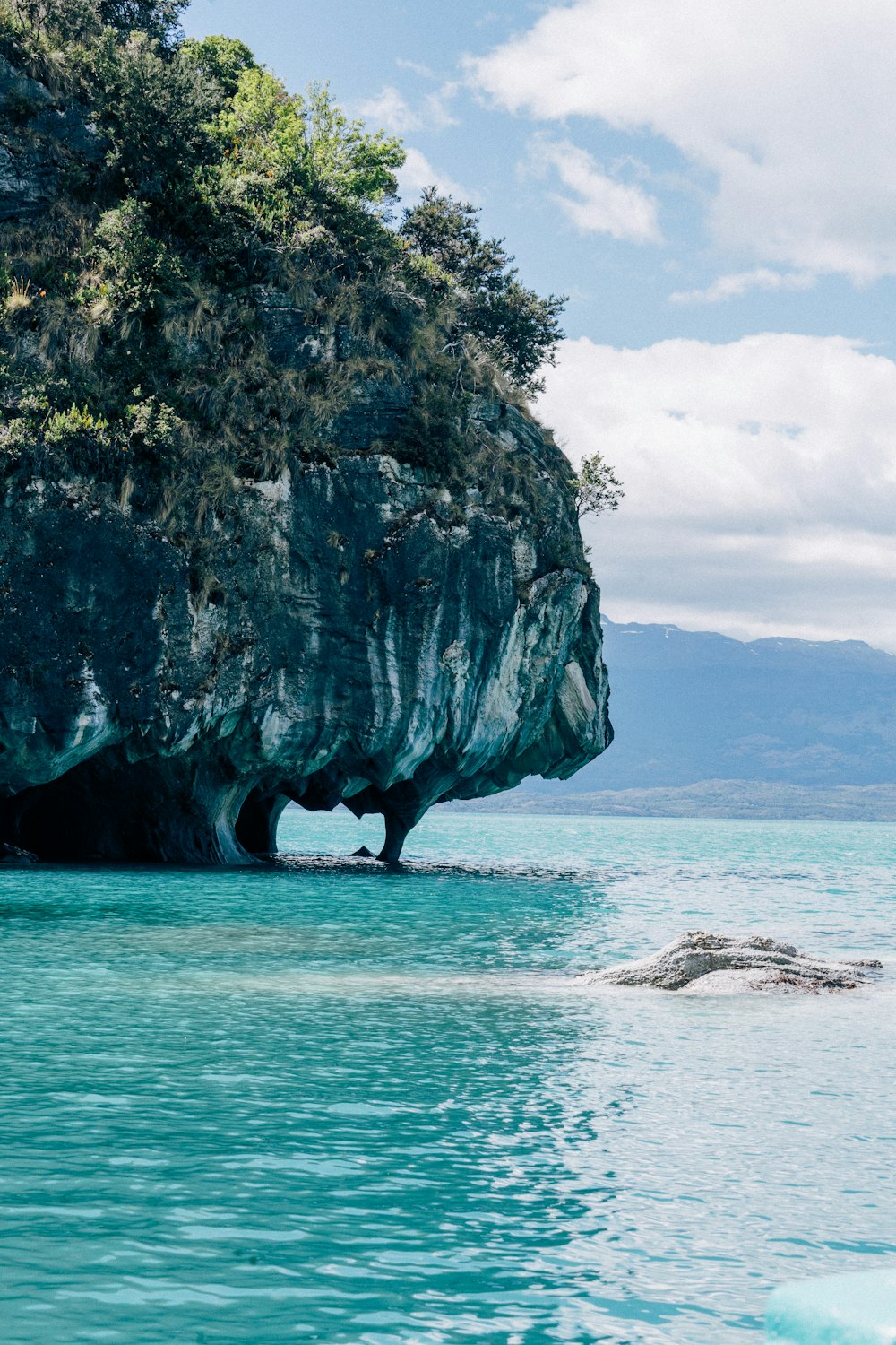 ein großer Felsen, der aus dem Wasser ragt